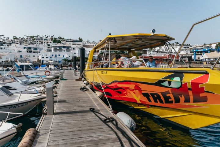 Yellow speedboat docked at marina with white buildings in the background.