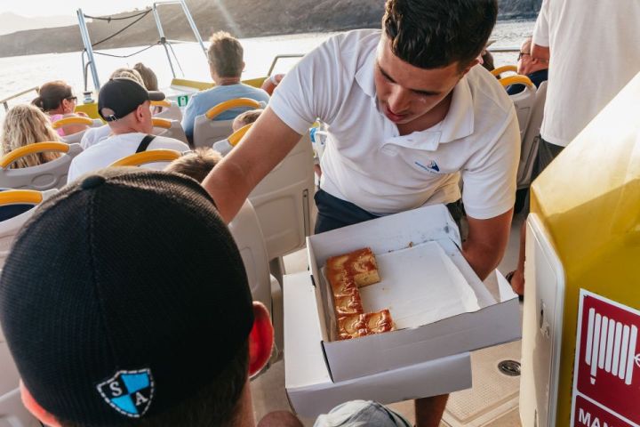 Person serving cake to passengers on a boat.
