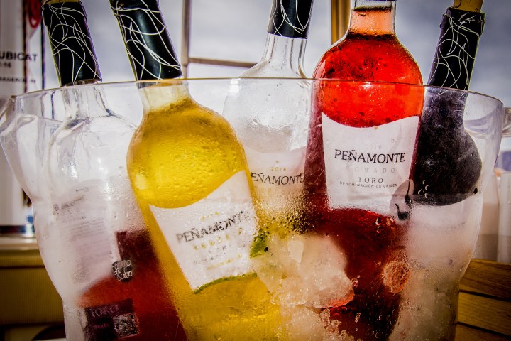 Wine bottles in ice bucket, labels partially visible, inside a glass container.