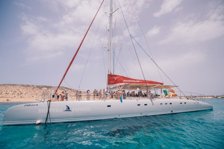 Large catamaran named Biofera Express on turquoise water with passengers onboard.