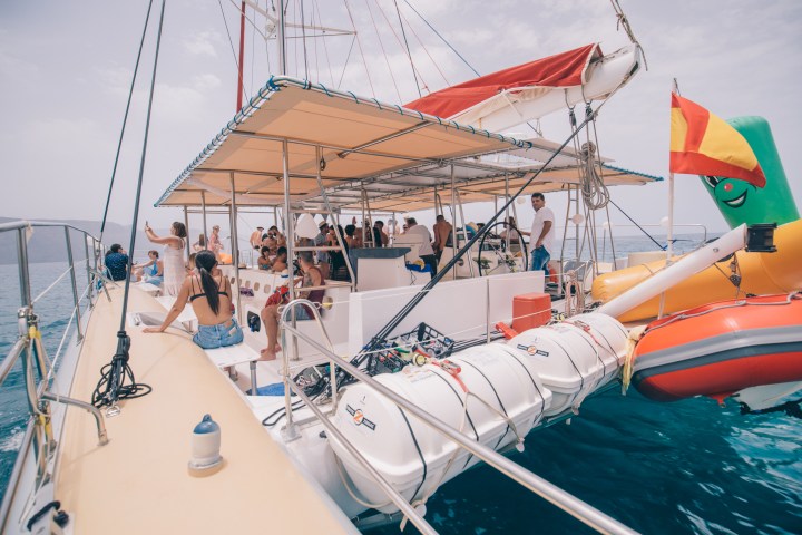 Group of people enjoying a boat ride on a sunny day with inflatables aboard.