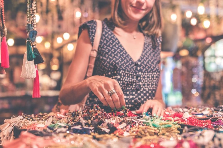 Woman browsing colorful jewelry at a market stall.